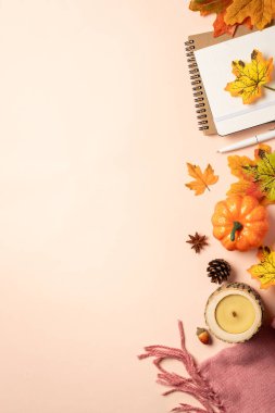 Sonbahar düz arka plan yatıyordu. Sarı arka planda sonbahar yaprakları, not defteri, eşarp, mum ve baharatlar.