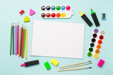 Çizim defteri, kalemler, suluboya boyalar ve mavi arka planda kalemler. Metin için alanı olan sanat yaratıcı bileşimi.
