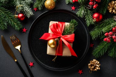 Noel sofrası. Noel yemeği. Siyah arka planda siyah tabaklar, çatal bıçak takımı ve süslemeler. Kopyalama alanı olan düz.