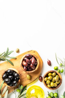 Tahta kaselerde zeytin yağı ve beyaz masada taze dallar. Üst görünüm resim kopyalama alanı.