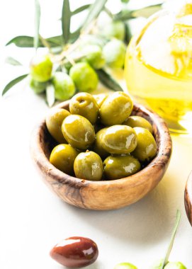 Beyaz masadaki kasede yeşil zeytin var. Kapat..