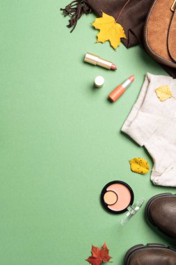 Autumn flat lay background. Warm cloth, bag and cosmetics. Woman cloth and beauty products with fallen leaves.