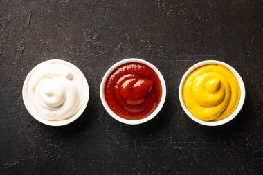 Siyah arka planda ketçap, mayonez ve hardal var. Üst görünüm.