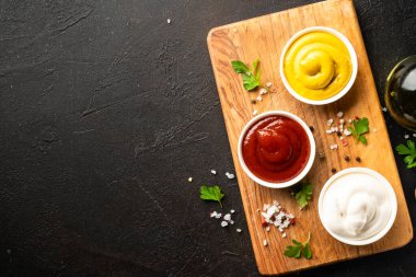 Kesme tahtasında ketçap, mayonez ve hardal var. Üst görünüm, tasarım için alan.