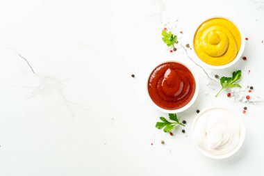 Sos kaseleri - mayonez, hardal, beyaz arka planda ketçap. Tasarım için alanı olan üst görünüm.