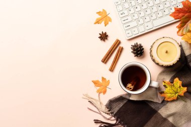 Sonbahar ofis masası. Laptop, bir fincan çay, baharatlar ve dökülen yapraklı eşarp. Metin için boşluk ile düz uzandı.