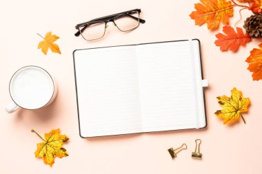 Not defteri, bir fincan kahve ve sarı yapraklar. Metin için boşluk ile düz uzandı.