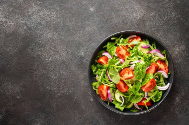 Yapraklı ve sebzeli taze salata. Siyah üzerine üst görünüm.