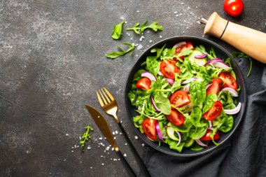 Yapraklı ve sebzeli taze salata. Siyah üzerine üst görünüm.