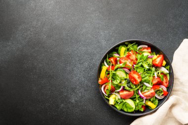 Yapraklı ve sebzeli taze salata. Siyah üzerine üst görünüm.