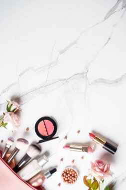 Beyaz mermer arka planda çiçekli ürünler uydur. Kozmetik palet, fırçalar ve rujlar. Kopyalama alanı olan üst görünüm.