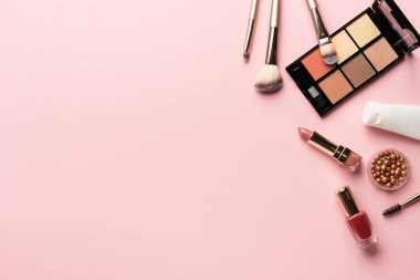 Makyaj ürünleri pembeye yatar. Göz farı, fosforlu kalem, krem, ruj ve kozmetik fırçalar..