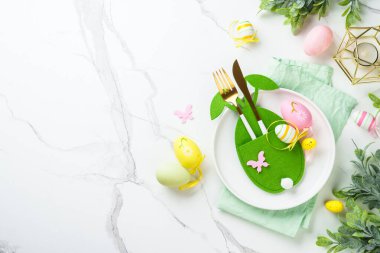 Beyaz arka planda Paskalya sofrası. Beyaz tabak, çatal bıçak takımı ve paskalya süslemeleri. Düz yatıyordu.