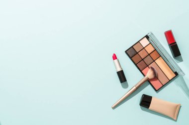 Profesyoneller için gölgelerle makyaj ürünleri. Mavi arka planda düz uzandı.