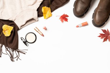 Sonbahar kumaşı ve aksesuarları. Atkı, kazak, ayakkabı ve yapraklı kozmetik ürünleri. Dizayn için alanı olan düz uzandı.