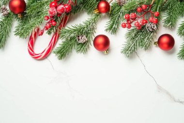 Noel arkaplanı beyazı üzerine kuruluydu. Noel kırmızı süslemeleri ve köknar ağacı. Kopyalama alanı olan kompozisyon.