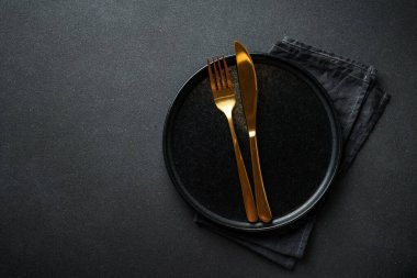 Siyah çatal bıçak takımlı siyah tabak. Kopyalama alanı olan düz.