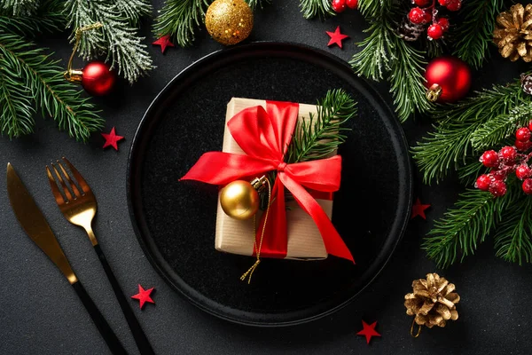 Noel sofrası. Noel yemeği. Siyah arka planda siyah tabaklar, çatal bıçak takımı ve süslemeler. Kopyalama alanı olan düz.