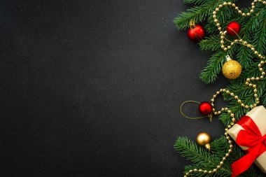 Noel arkaplanı düzdü. Şimdiki kutu, köknar ağacı ve siyah üzerine tatil süslemeleri..