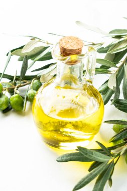 Beyaz masadaki şişede zeytin yağı ve taze zeytin dalı..