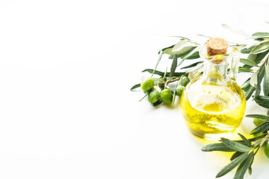 Beyaz masadaki şişede zeytin yağı ve taze zeytin dalı..
