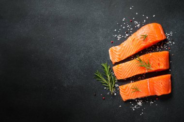 Siyah masada çiğ balık. Limon ve baharatlı somon filetosu. Kopyalama alanı olan üst görünüm.