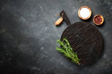 Baharatlı mutfak masası ve siyah arka planda kesim tahtası olan otlar. Metin için boşluk ile düz uzandı.