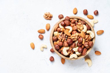 Beyaz arka planda fındık çeşitleri. Badem, fındık, ahşap kasede kaju. Üst görünüm