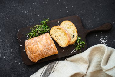 Ciabatta ekmeği tahtada siyah zemin üzerinde.