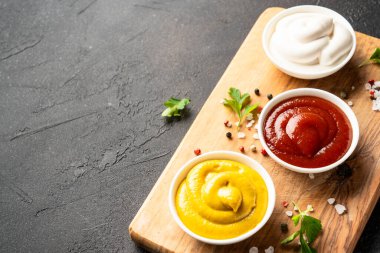 Siyah arka planda ketçap, mayonez ve hardal var..