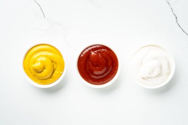 Sos kaseleri - mayonez, hardal, beyaz arka planda ketçap. Üst görünüm.