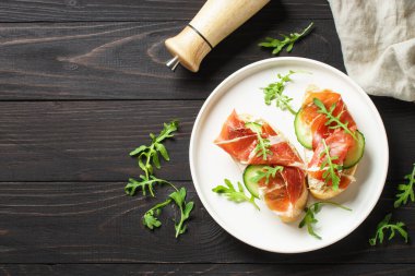 Aperatif crostini, krem peynirli sandviç, prosciutto, salatalık ve roka. Düz yatıyordu.