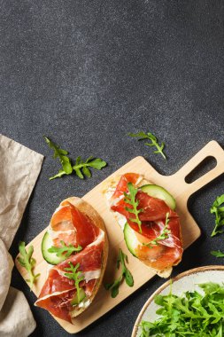 Krem peynirli sandviç, jambon, salatalık ve roka. Üst görünüm, dikey.