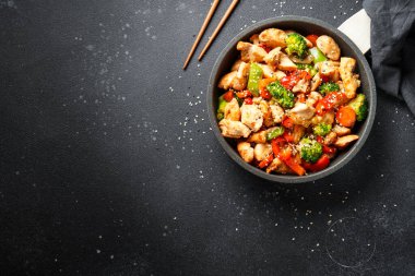 Sebzeli tavuk kızartması ve siyah arka planda susam. Kopyalama alanı olan üst görünüm.