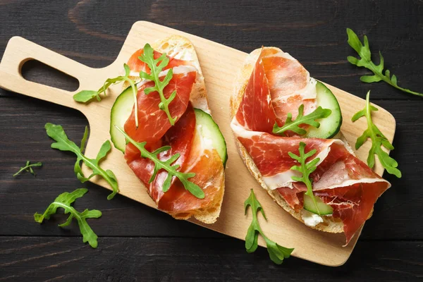 Sandviçleri krem peynirli, jambonlu, salatalıklı ve roka dilimli açın..