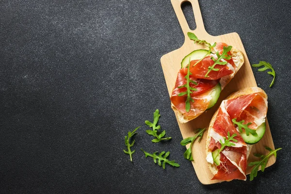 Krem peynirli sandviç, jambon, salatalık ve roka. Metin için boşluk olan üst görünüm.