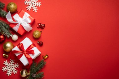 Noel arkaplanı düzdü. Noel süsleri ve Noel ağacıyla kırmızıda hediyeler. Kopyalama alanı olan düz resim.