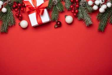 Noel arkaplanı düzdü. Noel süsleri ve Noel ağacıyla kırmızıda hediyeler. Kopyalama alanı olan düz resim.