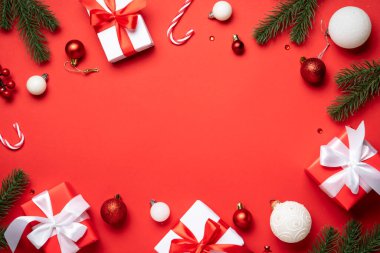 Noel arkaplanı kırmızıda yatıyordu. Noel süsleri, köknar ağacı ve hediyeler. Kopyalama alanı olan düz resim.