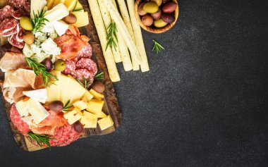 Antipasto tabağı. Peynir ve et - jambon, jambon, siyah masada servis masasında salam. Kopyalama alanı olan üst görünüm.