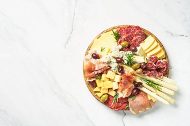 Antipasto tabağı. Tanışma ve peynir çeşitleri. Kopya alanı olan beyaz mermer tabloda üst görünüm.