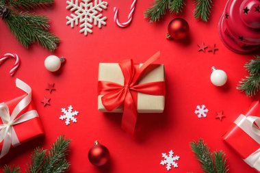 Kırmızı arka planda Noel hediyeleri. Hediye kutuları, köknar ağacı ve süslemeler..