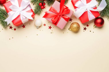 Noel hediyeleri, kırmızı süslemeler ve bej arka planda köknar ağacı. Dizayn için alanı olan düz resim.