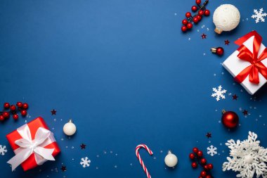 Noel arkaplanı. Kırmızı ve beyaz süslemeler ve mavi arka planda hediyeler. Noel aralığı. Dizayn için alanı olan düz resim.