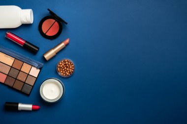 Kış makyajı, kozmetik ürünler. Yüz kremi, makyaj gölgeleri, ruj, mavi arka planda kozmetik fırçalar.