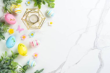 Paskalya düzlüğü arka plandaydı. Paskalya yumurtaları ve beyazın üzerindeki süslemeler. Kopyalama alanı olan düz.