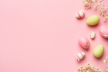 Paskalya arkaplanı pembeye uzanıyordu. Kopya alanı olan renkli yumurta ve çiçekler.