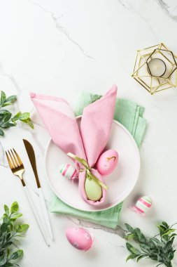 Beyaz arka planda bahar dekorasyonlu Paskalya sofrası. Beyaz tabak, çatal bıçak takımı ve renkli yumurta. Kopyalama alanı olan düz.
