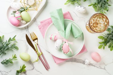 Paskalya yemeği geçmişi, beyaz arka planda tatil masası ayarı. Beyaz tabak, çatal bıçak takımı ve paskalya süslemeleri..