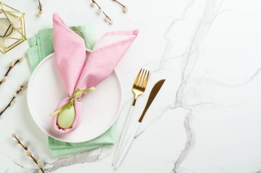 Beyaz arka planda süslemeleri olan Paskalya yemekleri. Beyaz tabak, çatal bıçak takımı ve komik paskalya süslemeleri..